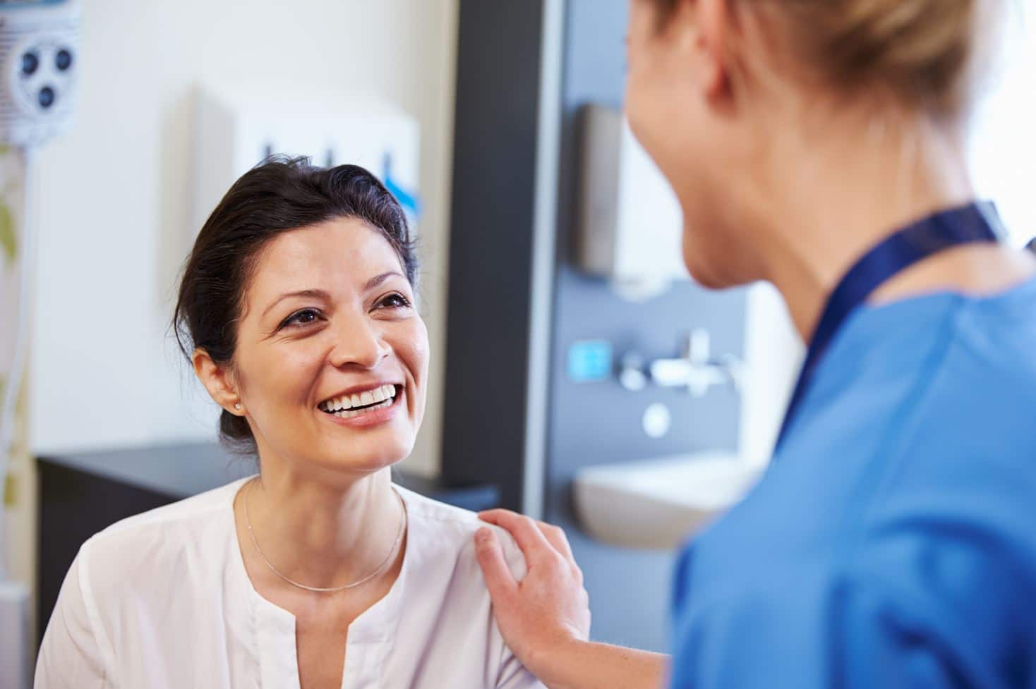 Image of a doctor holding up a mirror to the patient, the patient smiling and touching her nose